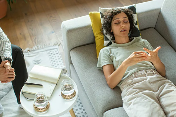 A woman lying on a couch, talking through her thoughts